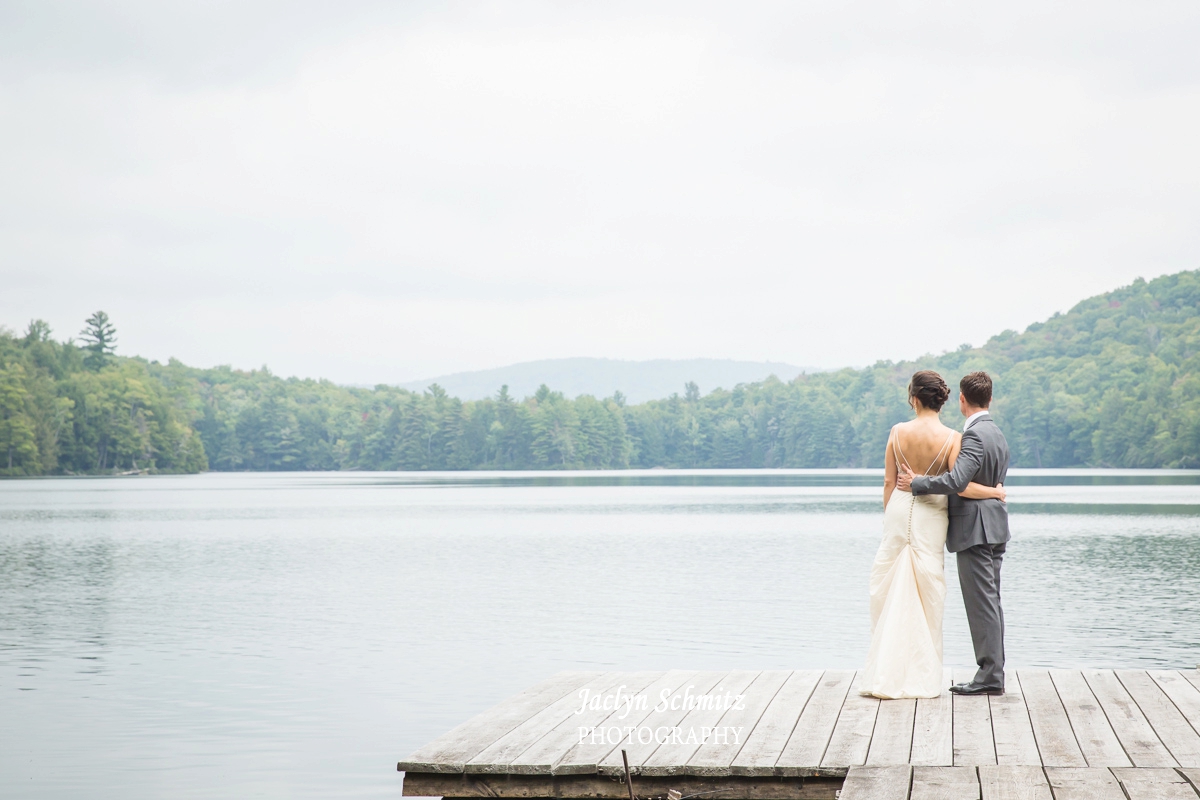 bride and groom gaze at lake on dock vt